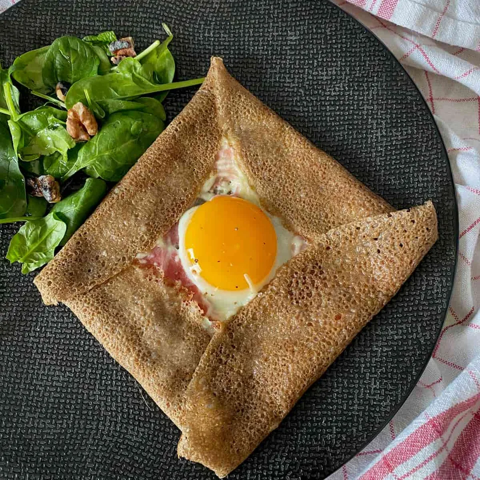 Buckwheat galette filled with ham, cheese and egg, with a side salad.