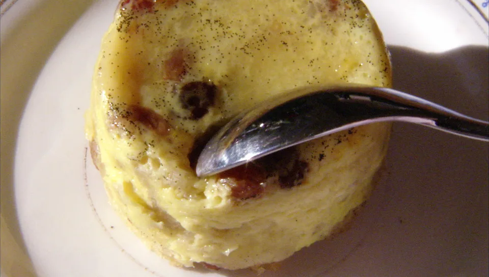 Individual diplomat pudding with raisins and vanilla on a plate with a spoon.